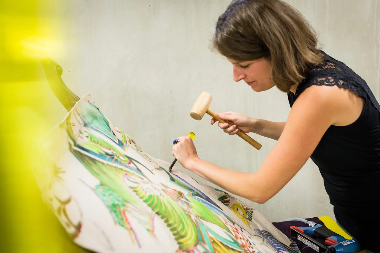 Artisane d'art travaillant au maillet sur un panneau peint, atelier lyonnais