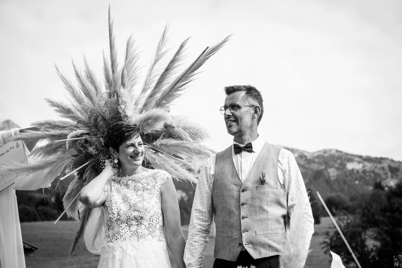 Mariés riant devant des herbes de la pampa, reportage de mariage en noir et blanc