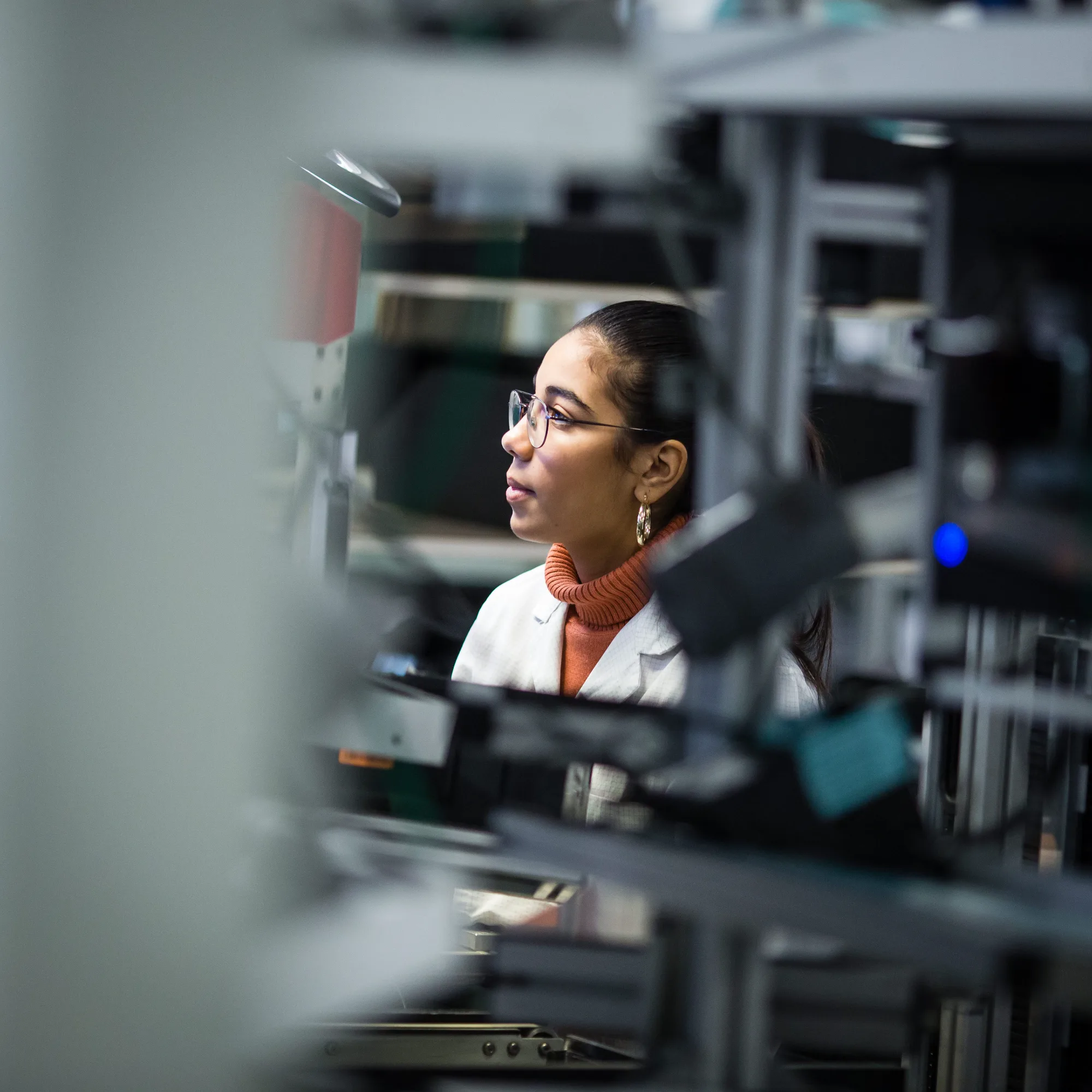 Technicienne en blouse blanche sur une ligne de production, site industriel du Rhône