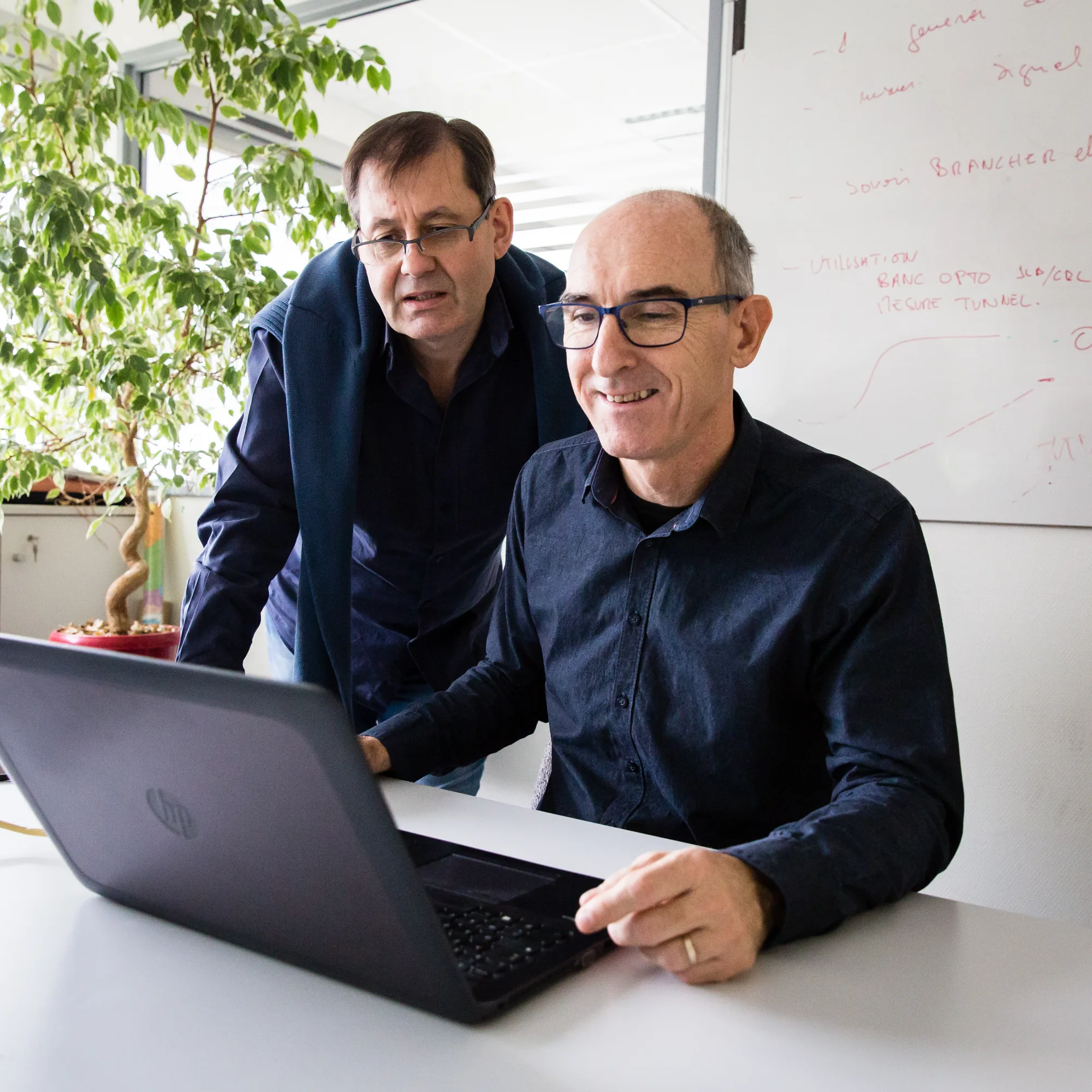 Deux collaborateurs devant un ordinateur portable, échange de travail en réunion