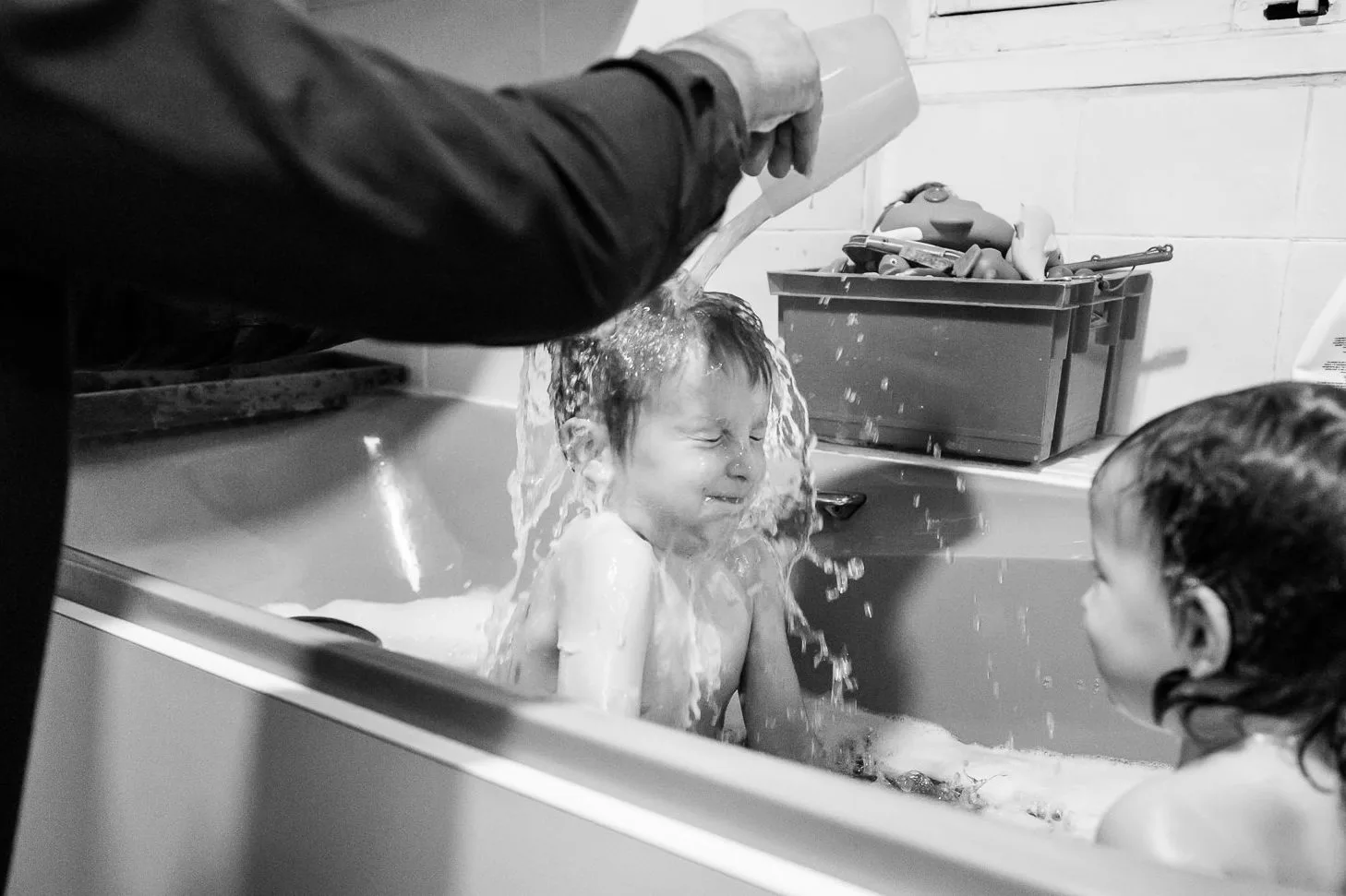 Enfant riant pendant le bain, photo de famille documentaire spontanée