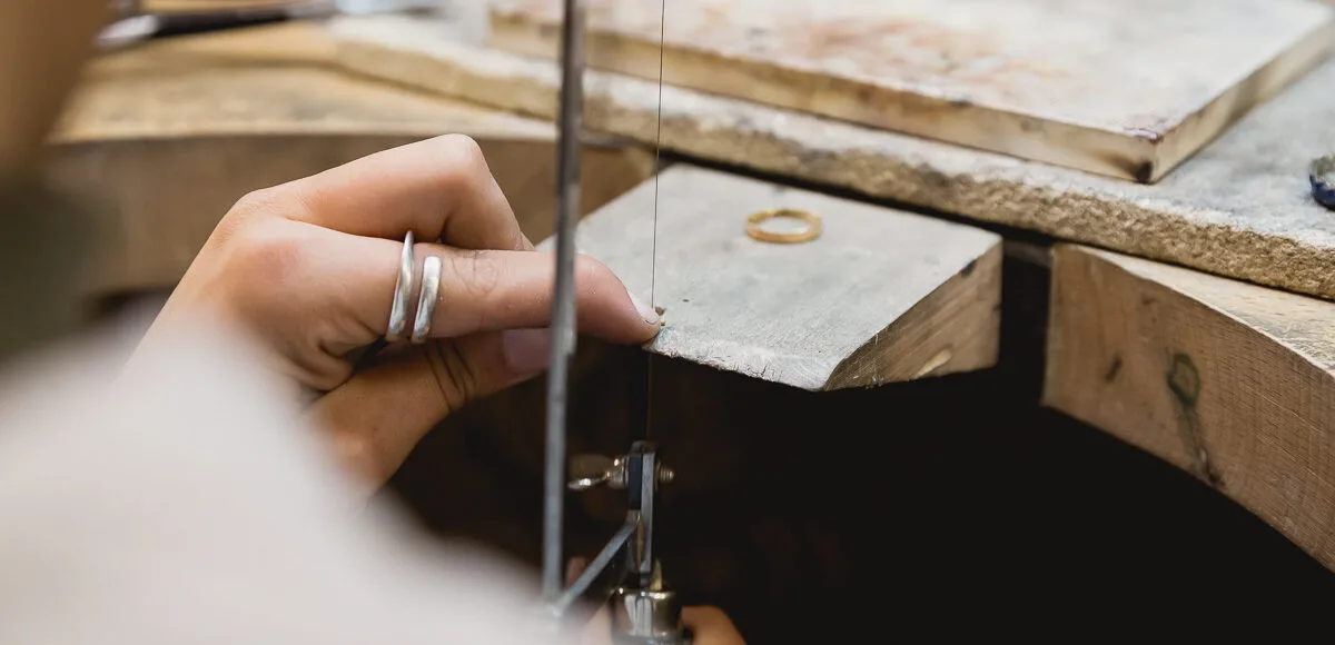 Mains d'un bijoutier à l'établi, gros plan sur le geste artisanal