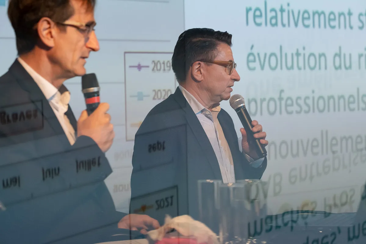 Deux dirigeants au micro devant un graphique projeté, conférence annuelle