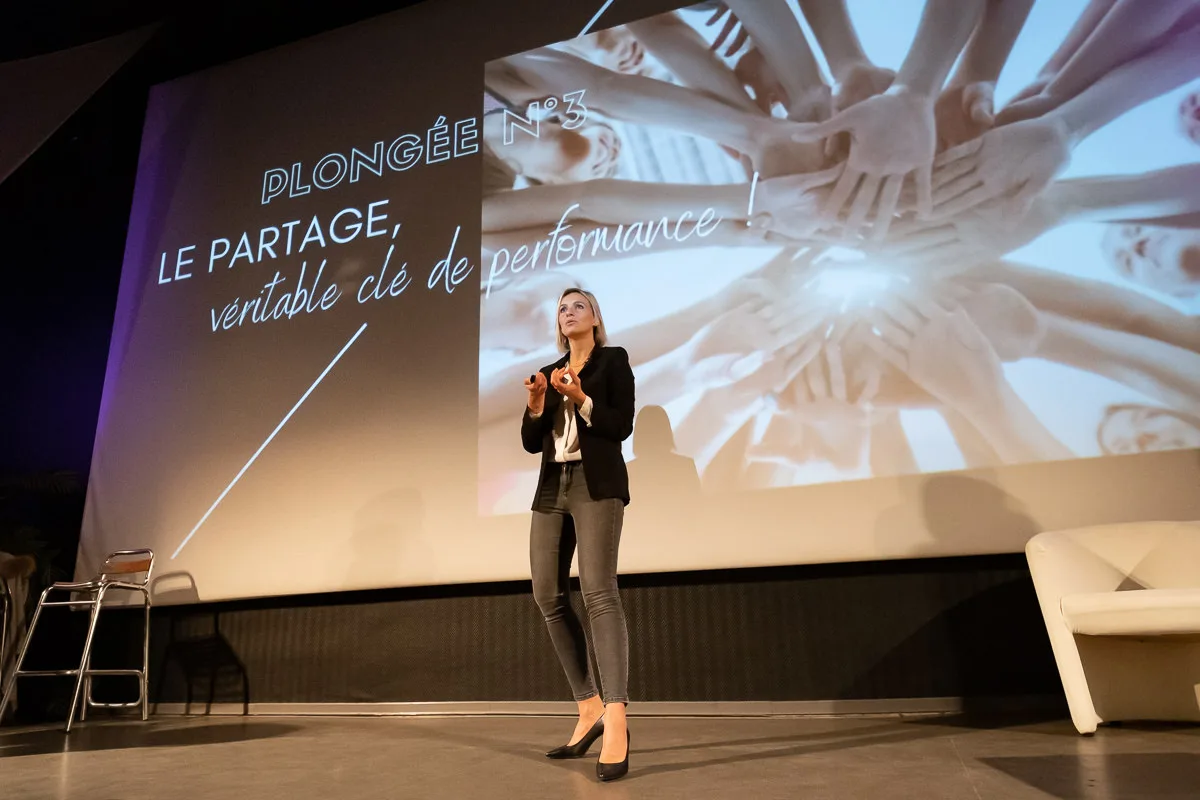 Conférencière sur scène devant son écran de présentation, séminaire d'entreprise à Lyon